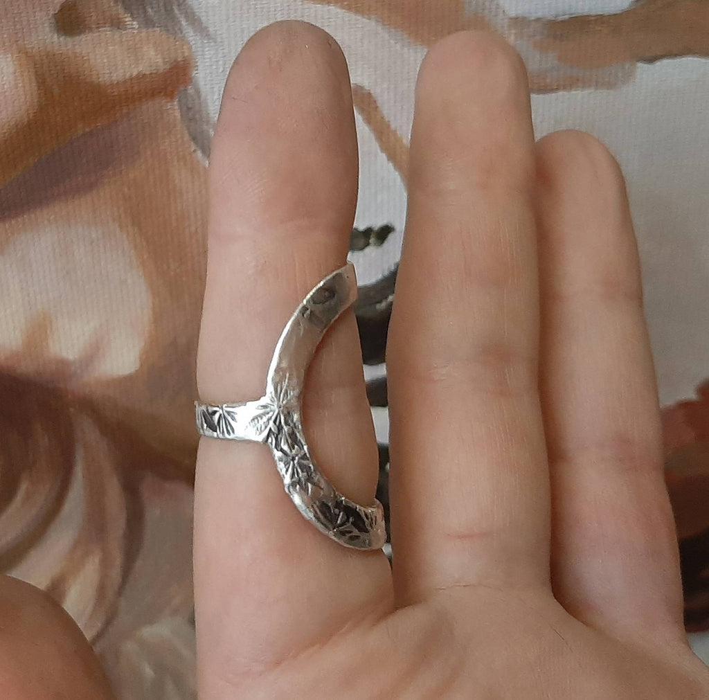 Close-up of a polished sterling silver finger support ring with handcrafted details