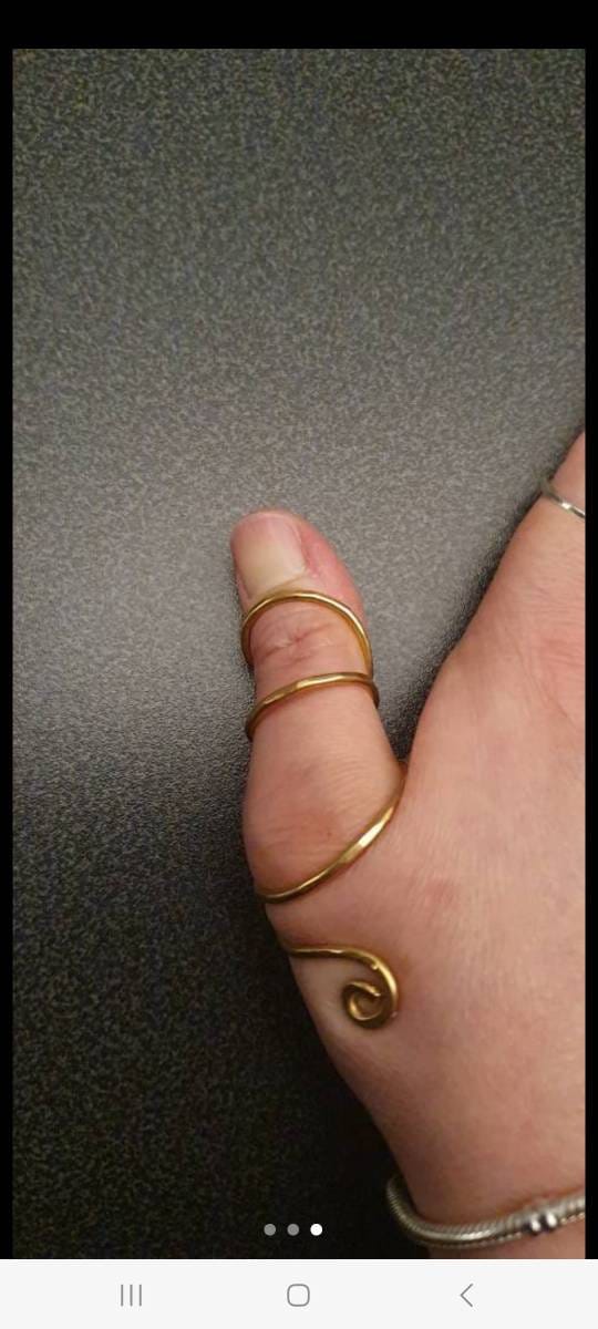 Close-up of a handmade yellow brass thumb splint ring with polished finish